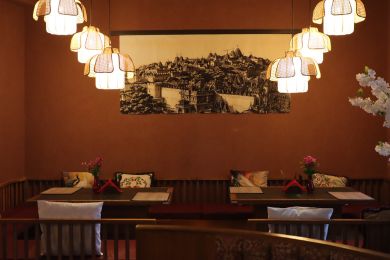 Cozy restaurant dining area with warm pendant lights and a long cushioned bench along the wall.